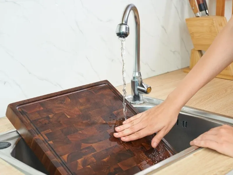 Rinsing wooden cutting board with warm water